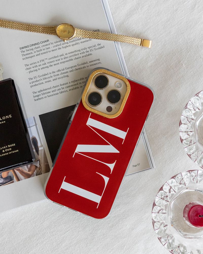 Funda premium roja con las iniciales LM y un marco de cámara dorado